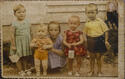 Old photograph of children wearing colorful clothes outside house